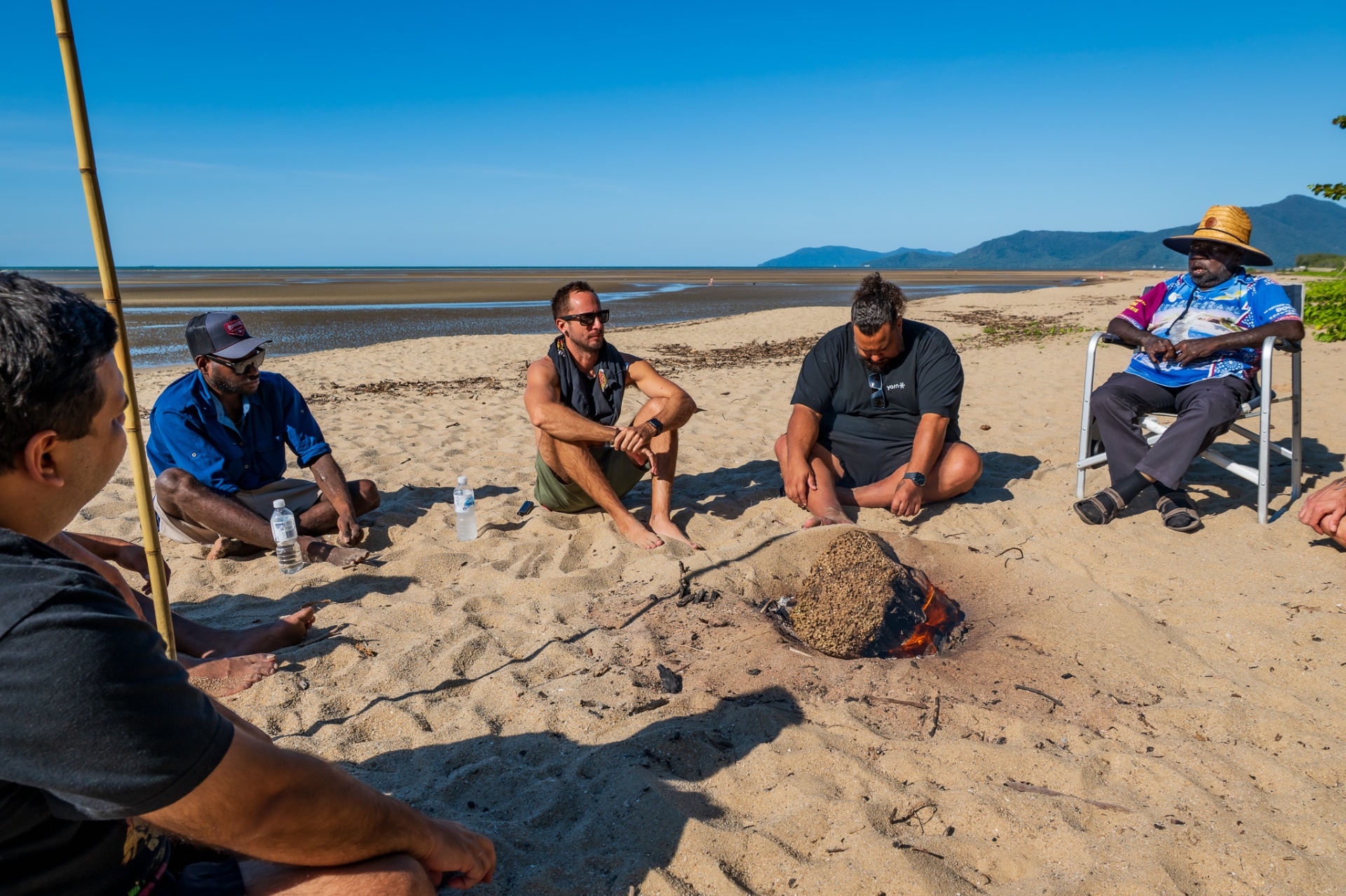 Men sitting around a beach fire sharing a yarn