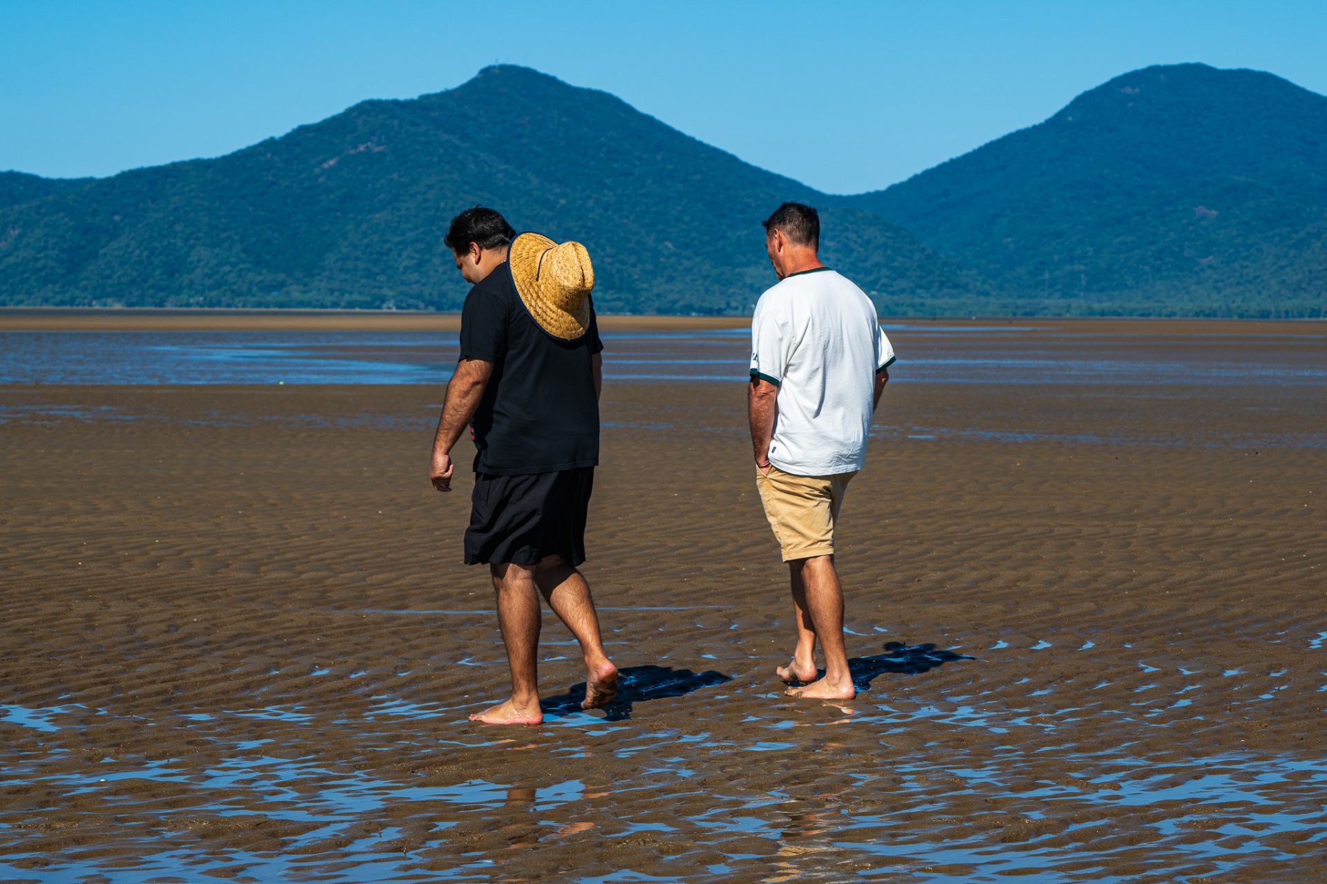 Two men walking together across tidal flats